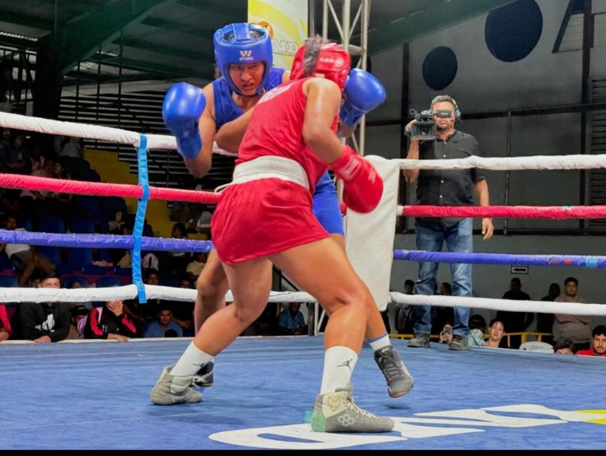 Boxing 2 - Neighbors to Nicaragua Two boxers spar in a ring: one in blue gloves and gear, the other in red; a cameraman watches from the background.