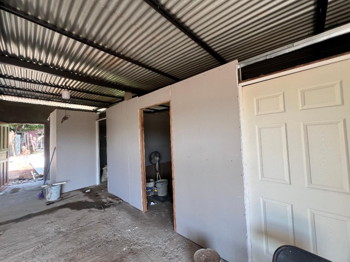 Under-construction interior with gray drywall walls, an open doorway, and a white panel door on the right.