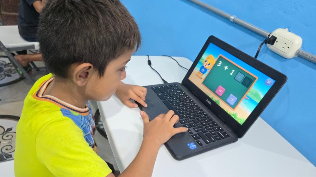 Young boy typing on a small Dell laptop, engaged with an educational math game on the screen.